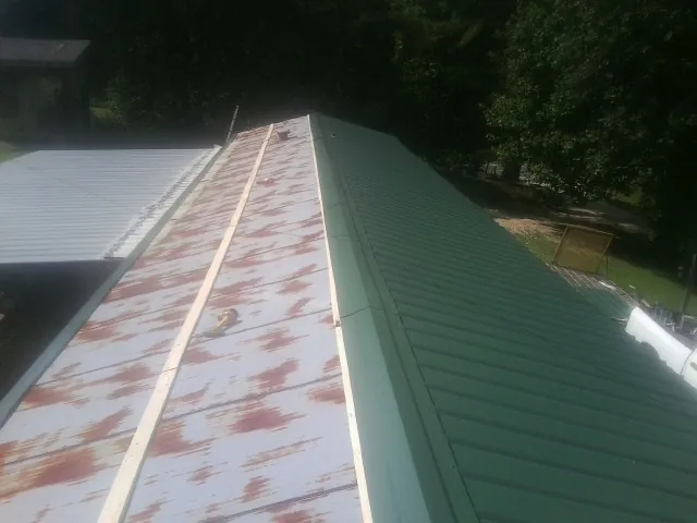 Old rusted panels beside newly installed green metal roofing — Wind Damage Roof Repair by Roofing Brothers in Norwalk
