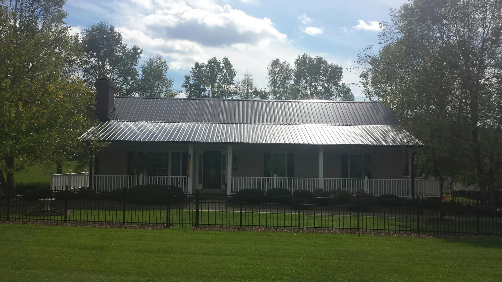Gray metal roof on a brick ranch with a full width front porch — Gutter Guard Installation work by our crew in Norwalk